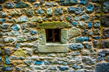Fregona, Treviso, Veneto, İtalya 'daki Caglieron parkındaki eski bir değirmenin taş duvarındaki küçük kare pencere.