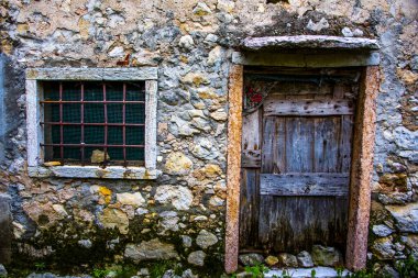 İtalya, Veneto 'daki Chiampo Vadisi' nde taş duvarlı eski ve yıpranmış bir ahşap kapı.