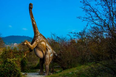 Uzak bir zamanda Jurassic Park 'ta, ağaçların ve kayaların arasında yaşayan bir dinozor.
