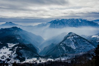 Karlı tepeleri ve sisli vadileri olan dağlık dağ tepeleri ve Tonezza, Vicenza, İtalya 'da mavi katmanlı dağ manzaraları.