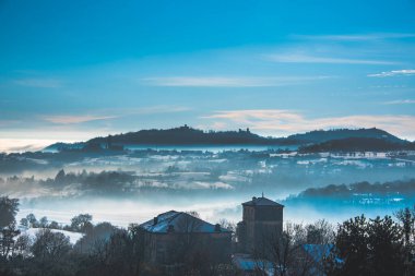Karlı tepeler, İtalya 'nın Vicenza şehrinde, ön planda bir evle sise gömüldü.