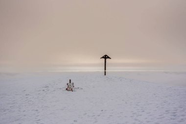 İtalya 'da Recoaro Mille, Vicenza' da dağ zirvesinin tepesinde kar ve bulutlarla işaretlenmiş ahşap haç.