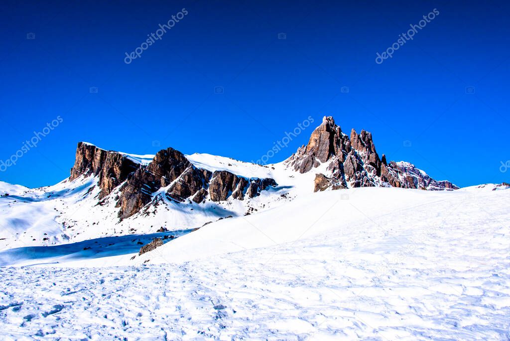 peaks of the Dolomites with snow, alpine valleys blue sky white clouds, snow tracks in the Zoldo valley, Belluno, Italy