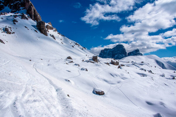 peaks of the Dolomites with snow, alpine valleys blue sky white clouds, snow tracks in the Zoldo valley, Belluno, Italy