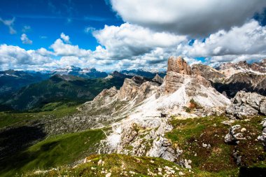 İtalya 'nın Cortina d' Ampezzo Belluno bölgesindeki Falzarego geçidinde Dolomitlerin yeşil çayırlarında kar ve pembe kayalarla bahar manzarası.