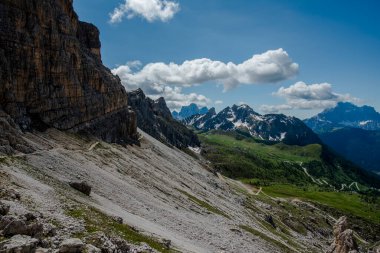 İtalya 'nın Cortina d' Ampezzo Belluno bölgesindeki Falzarego geçidinde Dolomitlerin yeşil çayırlarında kar ve pembe kayalarla bahar manzarası.