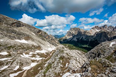 İtalya 'nın Cortina d' Ampezzo Belluno bölgesindeki Falzarego geçidinde Dolomitlerin yeşil çayırlarında kar ve pembe kayalarla bahar manzarası.