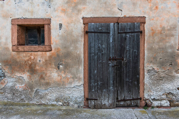 old wooden door with square window and orange frame in Farra D'alpago on the lake of Santa Croce Belluno Italy