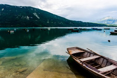 Santa Croce Belluno Gölü 'nün dolomitlerine yansıyan gölde demirlemiş eski ahşap balıkçı tekneleri.
