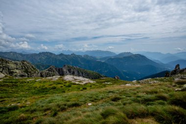 İtalya, Pieve Tesino yakınlarındaki Lagorai dağlarının geniş alp manzarası, kayan çimenli yamaçlar, pürüzlü tepeler ve uzak mavi ufuklara sahip..