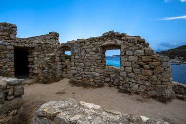 Korsika, Fransa 'da denize bakan antik taş kalıntıları. Terk edilmiş kıyı mimarisi, kemerli açıklıkları, pürüzsüz dokusu ve sakin Akdeniz manzarası.