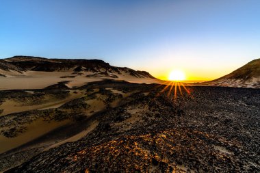 Parlak gün doğumu çöl tepelerinde ve kumlu vadilerde uzun vatozlar oluşturur. Dramatik ışık ve temiz geometri, ticari kullanım için derin yalnızlık ve ham çöl atmosferi taşır.