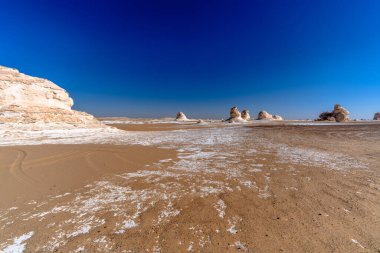 Mısır 'ın Giza yakınlarındaki uzak kireçtaşı oluşumlarına doğru kumlu çöl zemininden alçak görüş açısı güçlü bir derinlik ve izolasyon hissi yaratıyor..
