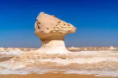 Mısır 'ın Giza yakınlarındaki Beyaz Çöl' de derin mavi bir gökyüzüne karşı izole bir şekilde duran kireç taşı şeklindeki belirgin mantar oluşumu..