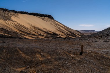 Giza yakınlarındaki Mısır çöllerinde uzak araçlar ve tepelerle uzanan uzun düz bir yol. İlerleme, mesafe ve izole seyahat yolları için metafor.