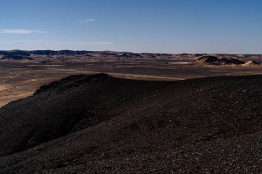 Giza yakınlarındaki Mısır çöllerinde uzak araçlar ve tepelerle uzanan uzun düz bir yol. İlerleme, mesafe ve izole seyahat yolları için metafor.