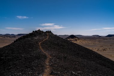 Giza yakınlarındaki Mısır çöllerinde uzak araçlar ve tepelerle uzanan uzun düz bir yol. İlerleme, mesafe ve izole seyahat yolları için metafor.