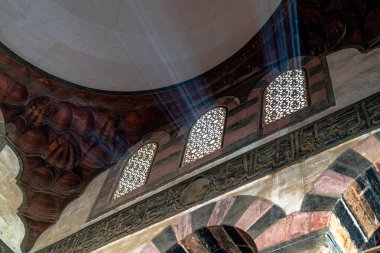 Mısır 'ın Giza kentindeki tarihi bir caminin iç mimarisi. Güneş ışığı desenli pencerelerden süzülüp süslemeli kemerleri ve huzur dolu ruhsal boşluğu ortaya çıkarıyor..