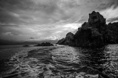 Fransa 'nın L' le-Rousse şehrinde dağlık kıyı şeridi ve dağınık bulutları olan mavi bir körfeze bakan kayalık manzarası. Seyahat, doğa ve kıyı manzarası temaları için.