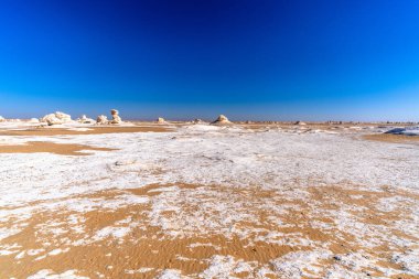 Farafra yakınlarındaki Beyaz Çöl 'ün geniş panoramik manzarası tebeşir zemin dokuları, uzak kaya oluşumları ve sancaklar ve geniş yerleşim alanları için mavi gökyüzü idealleri içerir..