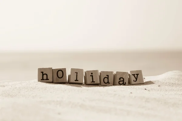 Holiday sezonu słowo z piaszczystej plaży tło w sepii — Zdjęcie stockowe