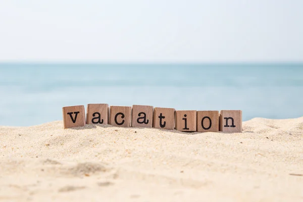 Vakantie woord op zonnige strand met oceaan achtergrond — Stockfoto