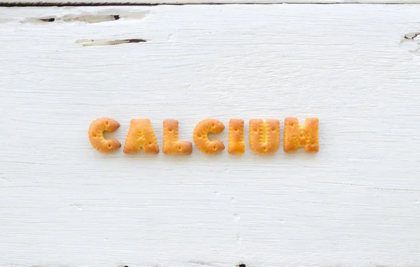 Word CALCIUM Alphabet craquelins sur fond bois — Photo