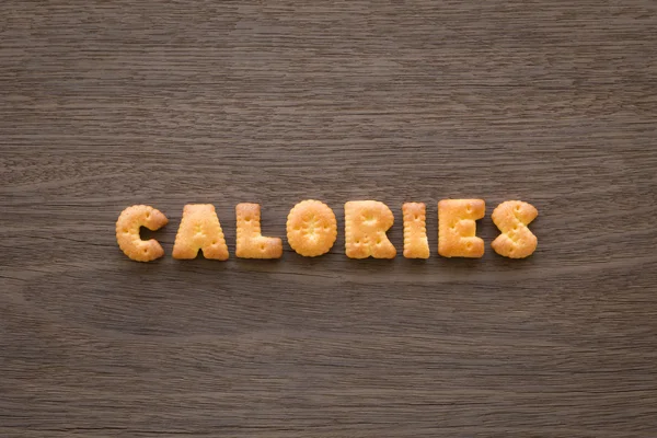Słowo kalorii alfabet herbatniki na tle drewna — Zdjęcie stockowe
