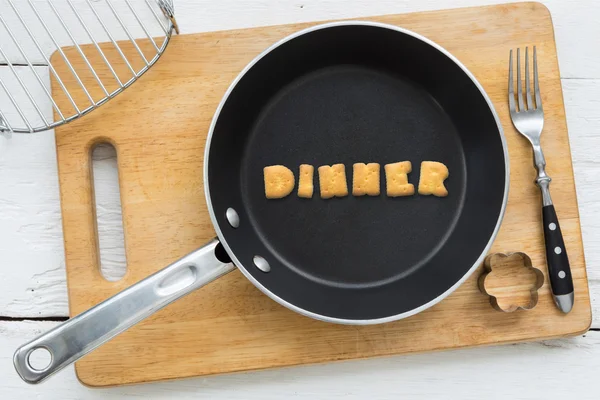 Alphabet crackers word DINNER putting in pan — Stock Photo, Image