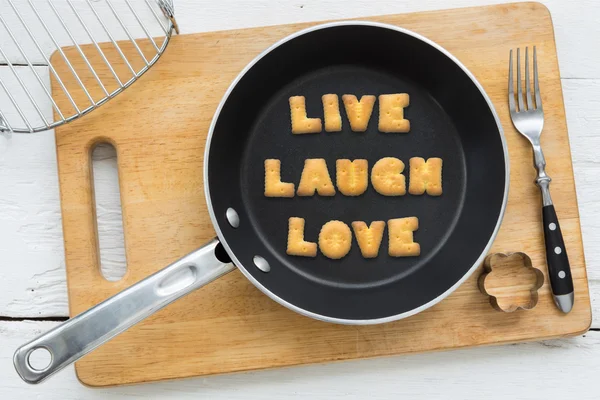 Letter cookies word LIVE LAUGH LOVE and kitchen utensils — Stock Photo, Image