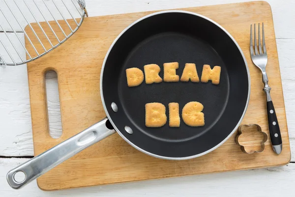 ตัวอักษรแครกเกอร์คํา DREAM BIG วางในกระทะ — ภาพถ่ายสต็อก