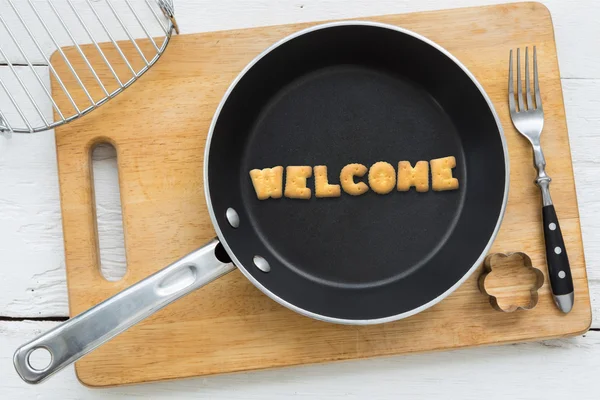 Cookie biscuits word WELCOME in frying pan — Stock Photo, Image