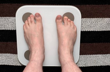 Erkeklerin çıplak bacakları terazide durur. Vücut ağırlığının ölçümü.