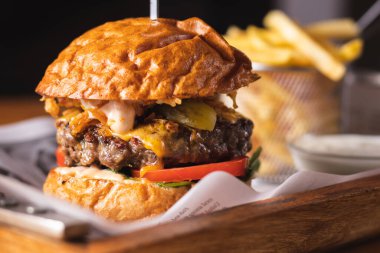 Tahta tepside servis edilen taze etli burger ve patates kızartması.