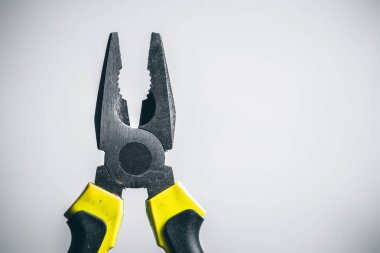 Beyaz arka planda sarı kerpeten. Beyaz arka planda sarı ve siyah saplı yeni pense. Üst Manzara. Tamir ya da inşaat aletleri. Profesyonel ergonomik aletler. Boşluğu kopyala.