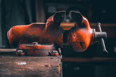 Kırmızı eski Mengene. Çeşitli işlem türleri için yedek ya da marangozluk aracı (kesme, delme, planlama...). Mengene ahşap masaya monte edilmiştir. Ahşap tezgahın üzerine monte edilmiş Ahlak Masası.