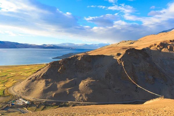 Blick vom Hügel auf die Berge, die Felder und den See tso moriri im Himalaya. — Stockfoto