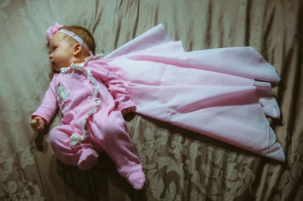 Image of cute little girl in pink suit and cloak indoor