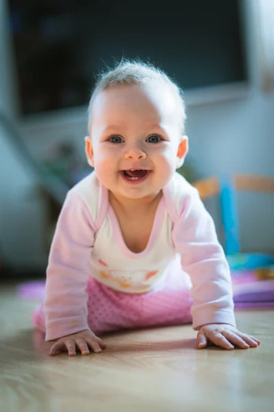 Schattige baby meisje verkenningen op all fours verdieping thuis. Glimlachen — Stockfoto