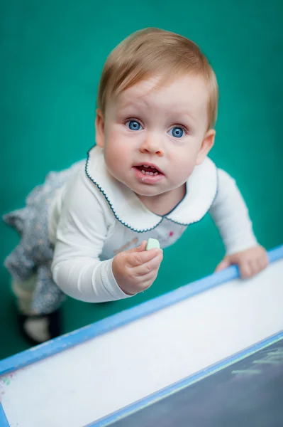 Baby stands near school chalk blackboard — Stockfoto