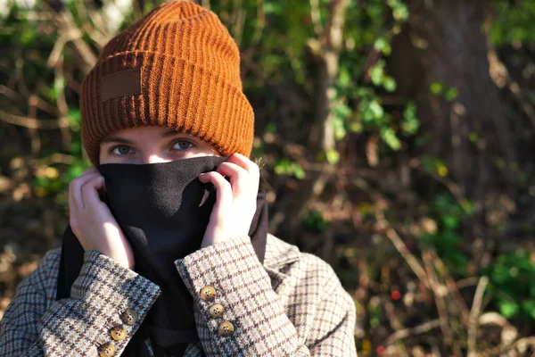 teenage girl covers her mouth and nose with a scarf as a protective against Convid-19 virus in the age of pandemic