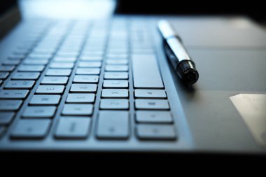 dizüstü bilgisayar klavyesi ve kalem - seçici odaklı uzak çalışma konseptini temsil eden fotoğraf