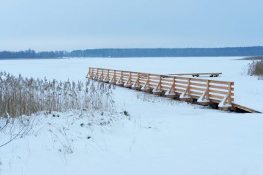 Kış manzarası donmuş göl üzerindeki iskeleyi kapladı.