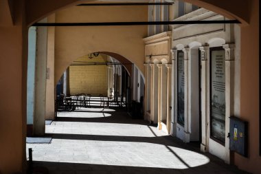 Arka planda rahat kafe sandalyeleri ve masaları olan klasik Rönesans atari salonları yere gölge düşürüyor.