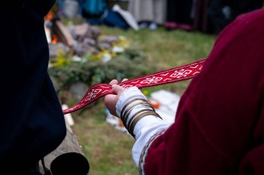Geleneksel Slav düğün töreni yeniden canlandırması - kırmızı işlemeli sınırı tutan kadın ellerinin yakın çekimi, tarihi bir giysi parçası
