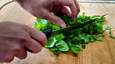 Kurutulmuş otlara hazırlanmak için taze fesleğen yapraklarını bıçakla doğramak.