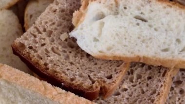 Dilimlenmiş ekşi ekmek, tahıllı ekmek ve sepetteki kabuklu çörekler. Parti yemekleri için mükemmel. Gerçek zamanlı video