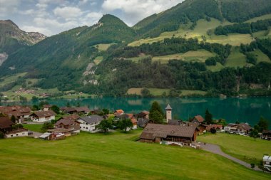 İsviçre 'nin Lungern köyünde geleneksel evleri ve eski kilise kulesi güzel zümrüt yeşili Lungerersee Gölü boyunca Alter Kirchturm, Obwalden kantonu, İsviçre Alpleri, Brunig Geçidi