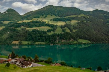 İsviçre 'nin Lungern köyünde geleneksel evleri ve eski kilise kulesi güzel zümrüt yeşili Lungerersee Gölü boyunca Alter Kirchturm, Obwalden kantonu, İsviçre Alpleri, Brunig Geçidi