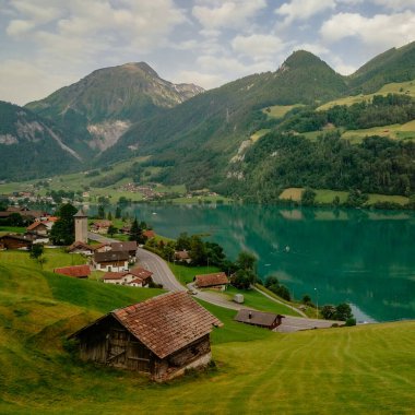 İsviçre 'nin Lungern köyünde geleneksel evleri ve eski kilise kulesi güzel zümrüt yeşili Lungerersee Gölü boyunca Alter Kirchturm, Obwalden kantonu, İsviçre Alpleri, Brunig Geçidi